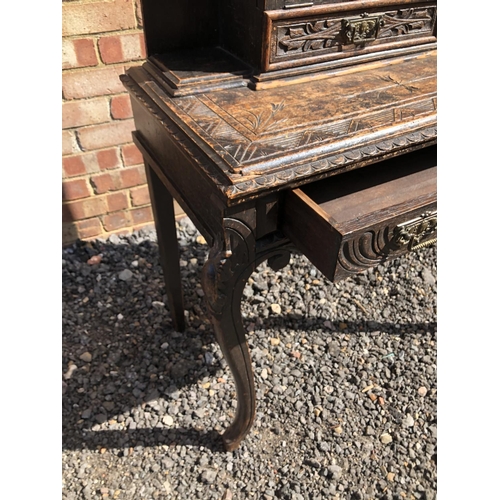 371 - A carved oak writing desk with a fall front to reveal pigeon holes and a leather writing surface