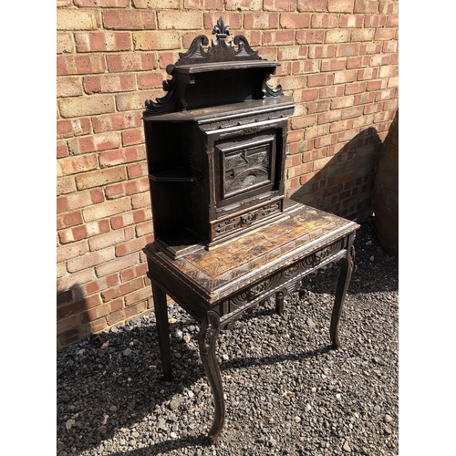 371 - A carved oak writing desk with a fall front to reveal pigeon holes and a leather writing surface