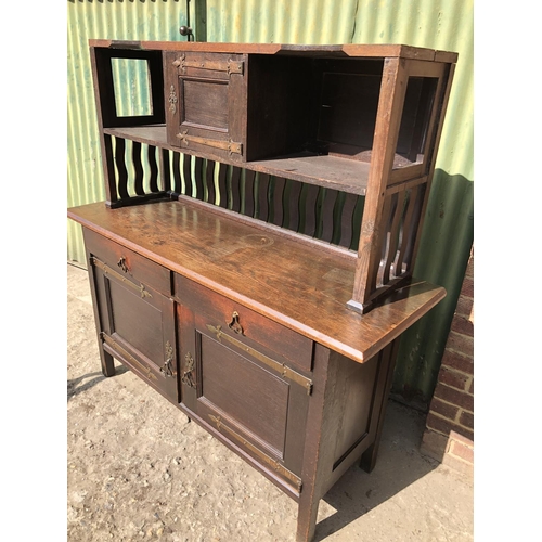 372 - An unusual Arts and crafts oak sideboard / dresser with long brass strap hinges and  brass drop hand... 