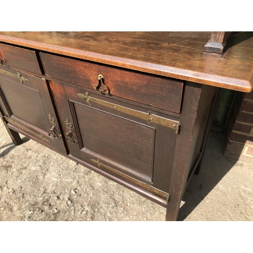 372 - An unusual Arts and crafts oak sideboard / dresser with long brass strap hinges and  brass drop hand... 