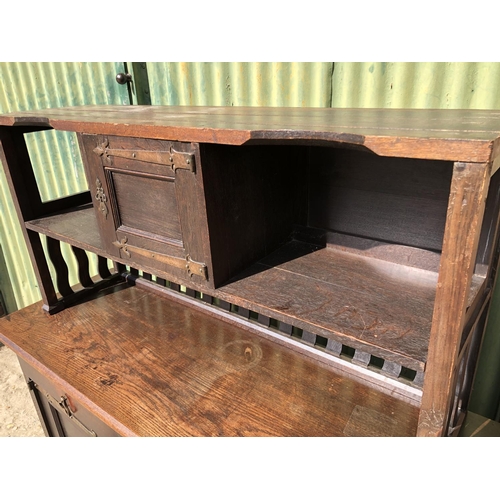 372 - An unusual Arts and crafts oak sideboard / dresser with long brass strap hinges and  brass drop hand... 