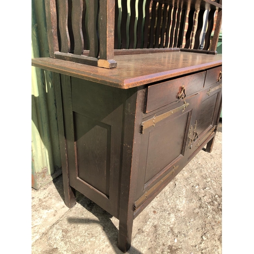 372 - An unusual Arts and crafts oak sideboard / dresser with long brass strap hinges and  brass drop hand... 