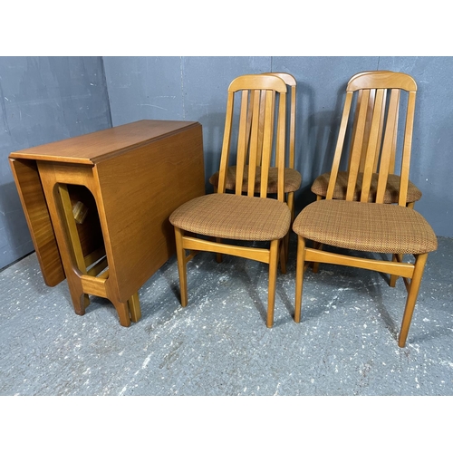 17 - A mid century teak drop leaf dining table together with four teak high back chairs