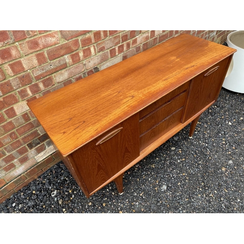 211 - A mid century teak sideboard, three central drawers flanked by two cupboards with sliding doors