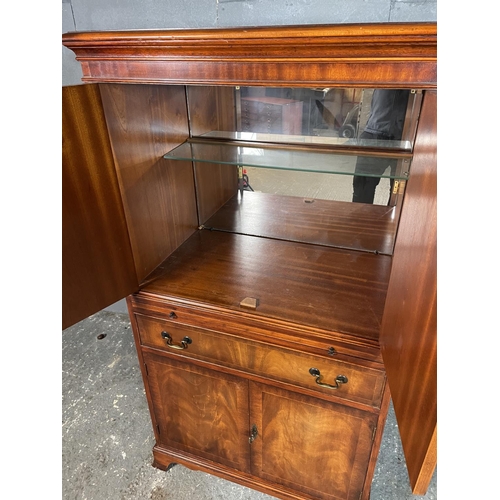 41 - A reproduction mahogany drinks cabinet, fitted with a mirror glass interior to the top, drinks slide... 