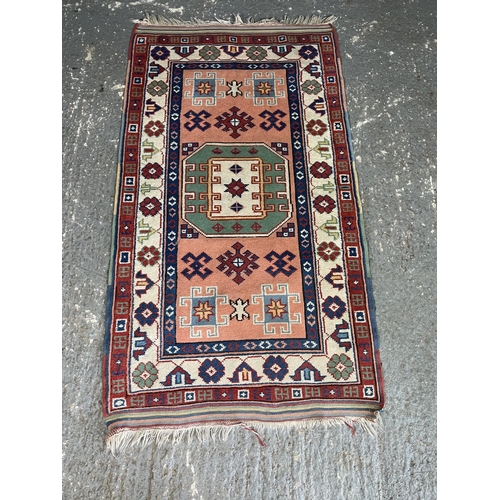 63 - A blue and red Aztec patterned rug 159 x 89 cm