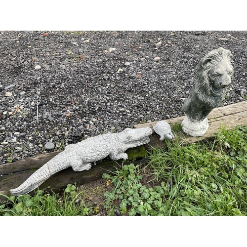 72 - A stone garden crocodile, together with a tortoise and lion garden statue