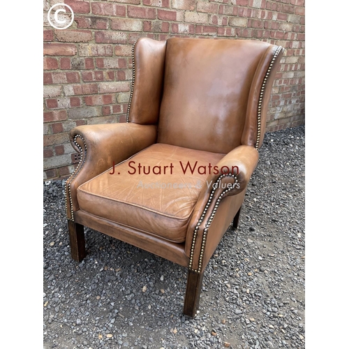 24 - A tan brown leather club style wing armchair