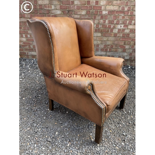 24 - A tan brown leather club style wing armchair