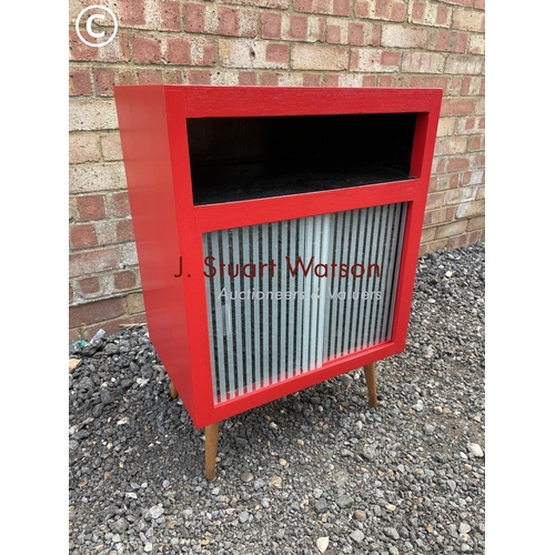 38 - A mid century red painted  record cabinet with glass sliding doors