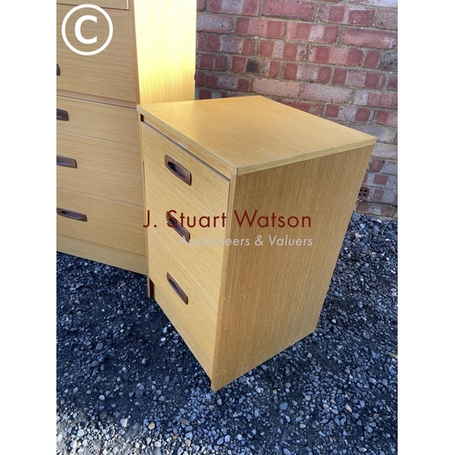 1 - A mid century teak effect tallboy chest together with a pair of three drawer bedsides