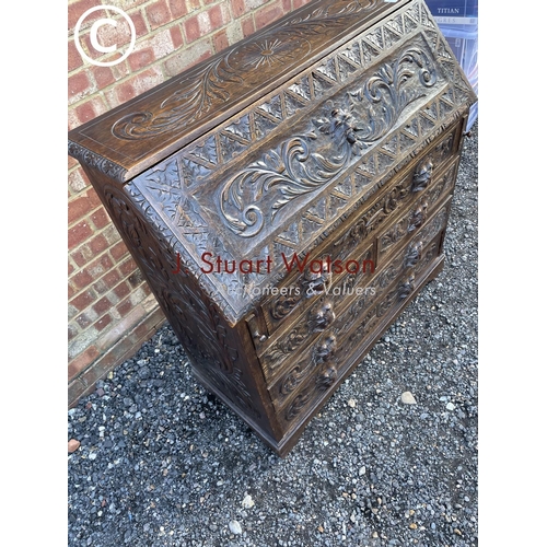 106 - A heavily carved oak bureau with fitted interior