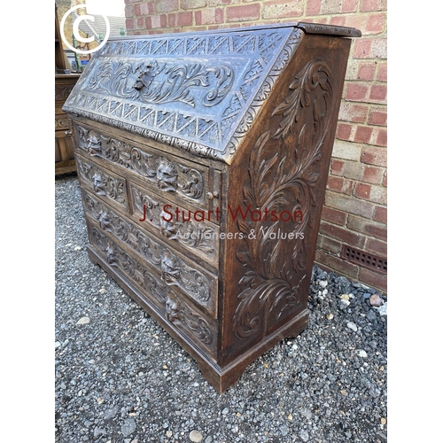 106 - A heavily carved oak bureau with fitted interior