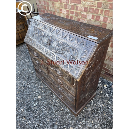 106 - A heavily carved oak bureau with fitted interior