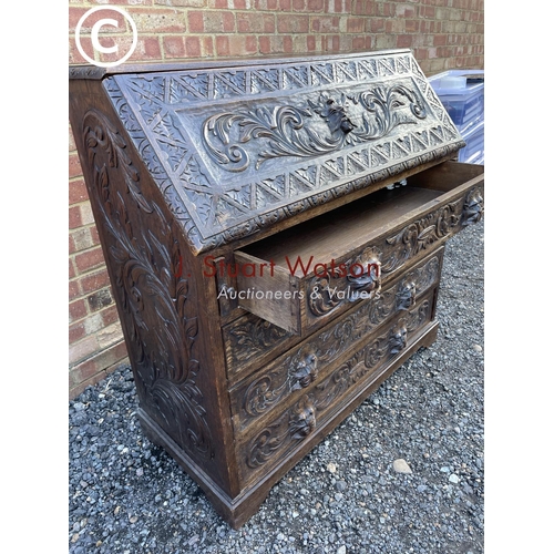 106 - A heavily carved oak bureau with fitted interior