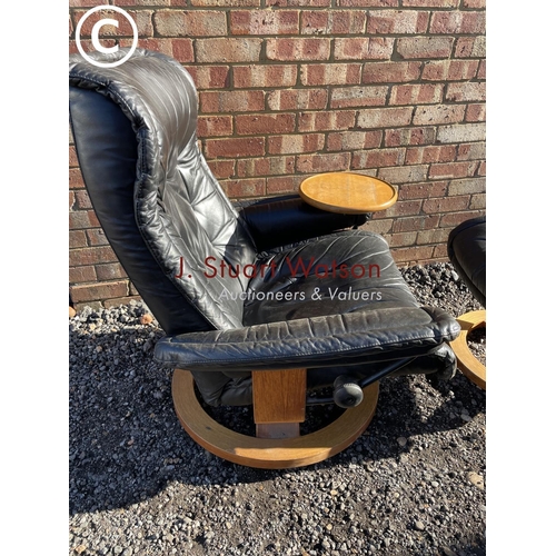 12 - An ekornes style black leather recliner chair with swivel drinks tray and matching footstool