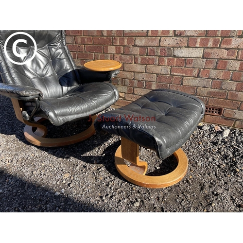 12 - An ekornes style black leather recliner chair with swivel drinks tray and matching footstool