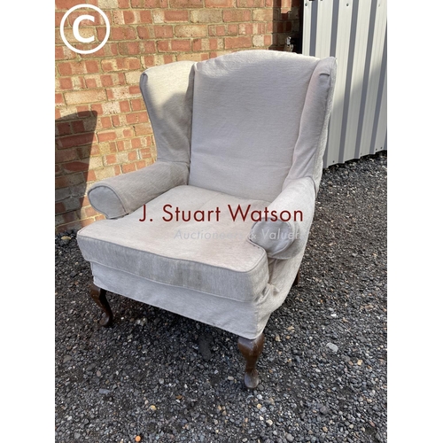 127 - A large beige upholstered wing back chair