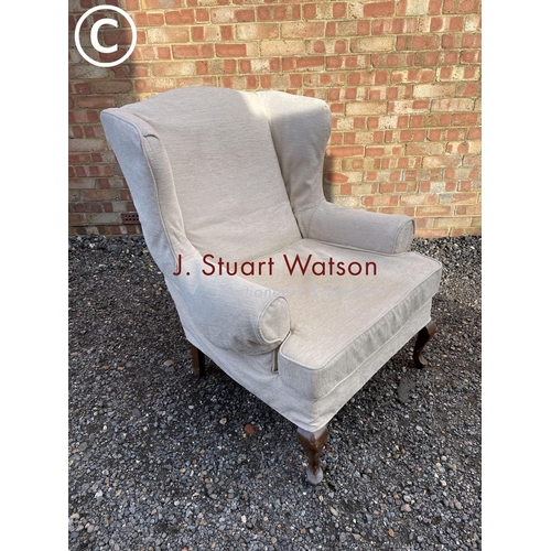 127 - A large beige upholstered wing back chair