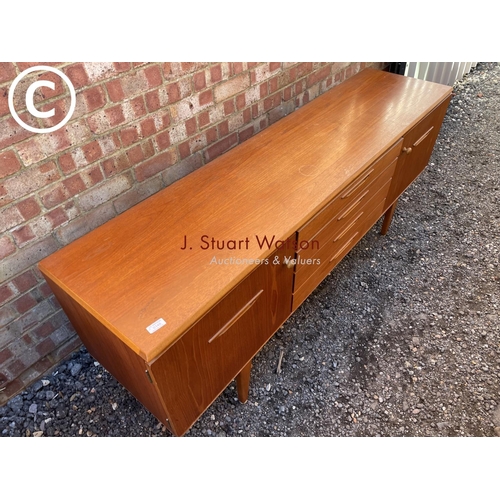 148 - a mid century teak sideboard with four central drawers flanked by cupboards