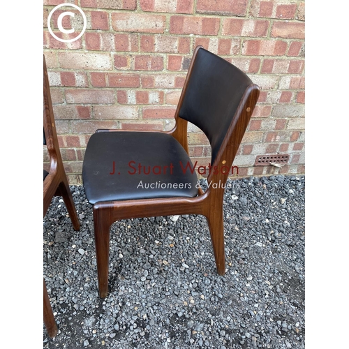 239 - A set of four Danish style teak framed dining chairs with black vinyl seats