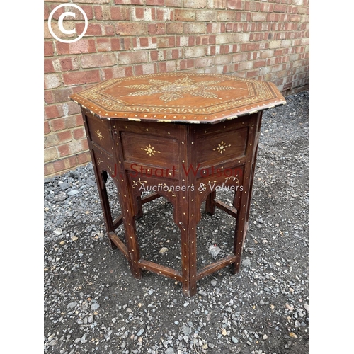 283 - An eastern style inlaid octagonal table on folding base