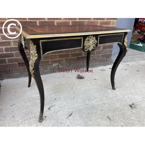 329 - An ebonised Victorian two drawer writing table with red leather top and brass mounts