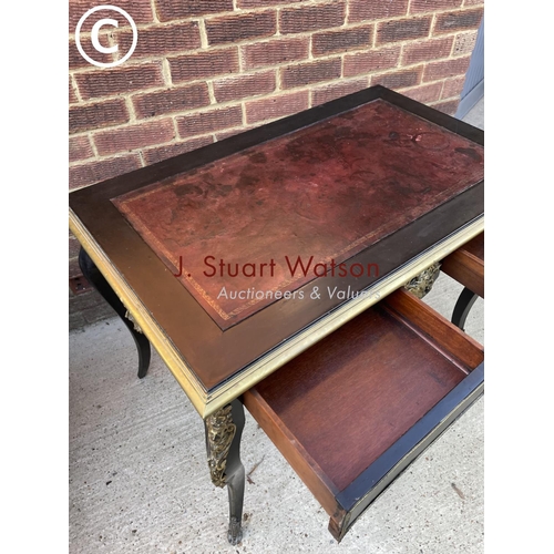 329 - An ebonised Victorian two drawer writing table with red leather top and brass mounts