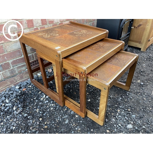 74 - A teak tiled top nest of three tables