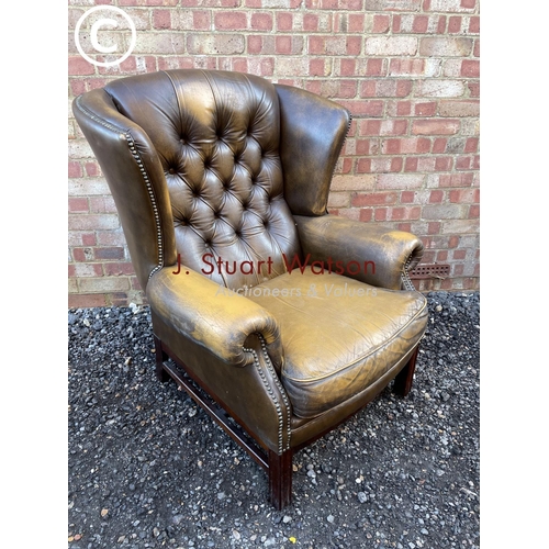 84 - A brown leather wing back Chesterfield armchair