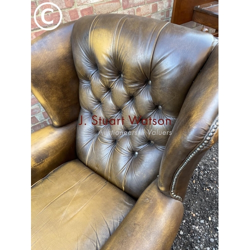 84 - A brown leather wing back Chesterfield armchair