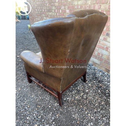 84 - A brown leather wing back Chesterfield armchair