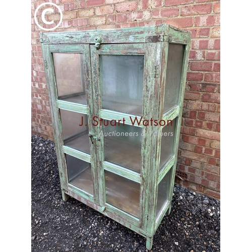 90 - A distressed green painted modern glazed cabinet with two internal shelves