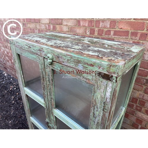 90 - A distressed green painted modern glazed cabinet with two internal shelves