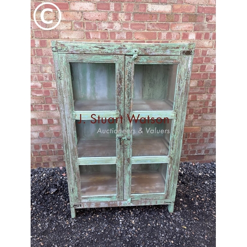 90 - A distressed green painted modern glazed cabinet with two internal shelves