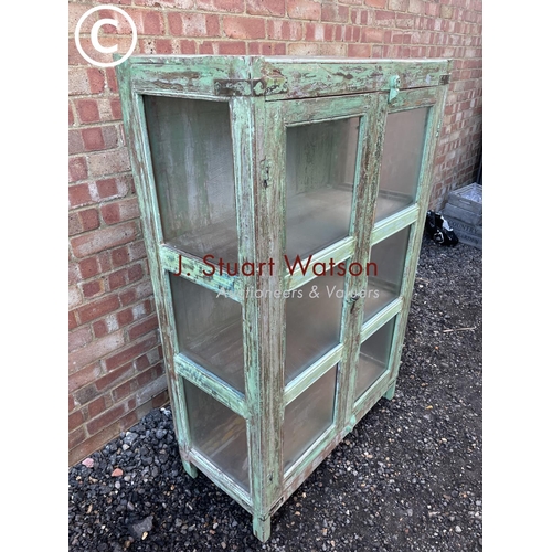 90 - A distressed green painted modern glazed cabinet with two internal shelves