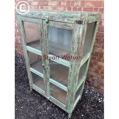 90 - A distressed green painted modern glazed cabinet with two internal shelves