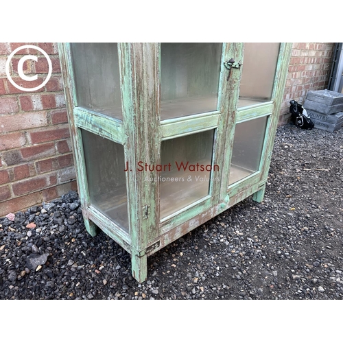 90 - A distressed green painted modern glazed cabinet with two internal shelves