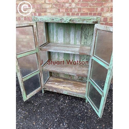 90 - A distressed green painted modern glazed cabinet with two internal shelves