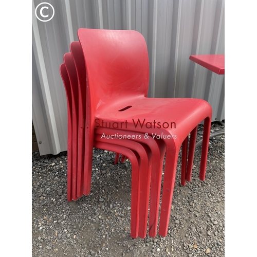 130 - A modernist red cafe table together with a set of red plastic stacking chairs