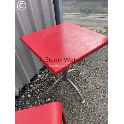 130 - A modernist red cafe table together with a set of red plastic stacking chairs