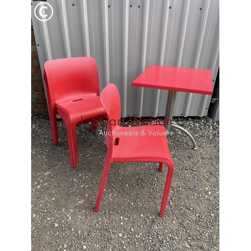 130 - A modernist red cafe table together with a set of red plastic stacking chairs