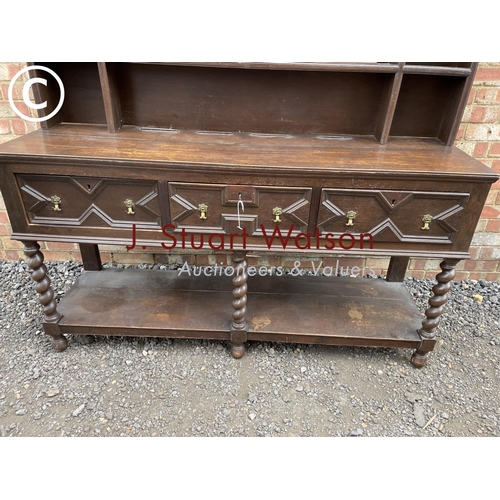 231 - An antique barley twist oak dresser with a plate rack back over three drawer base