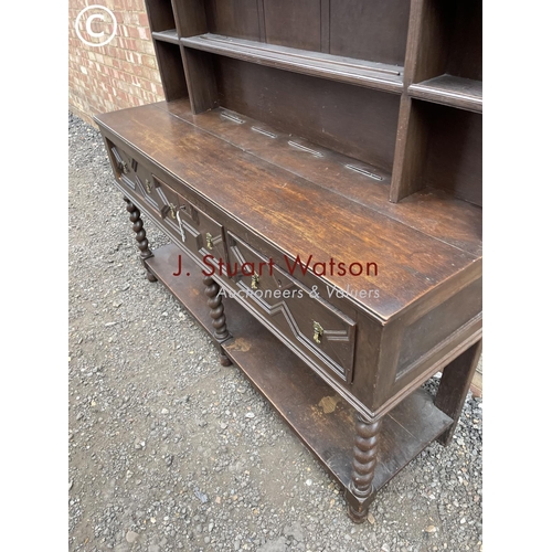 231 - An antique barley twist oak dresser with a plate rack back over three drawer base