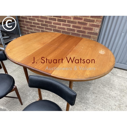 286 - G plan teak extending dining table together with four chairs with black vinyl seats