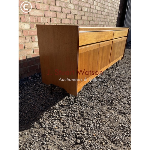 48 - A mid century teak sideboard with two drawers over four cupboard doors raised on hairpin legs