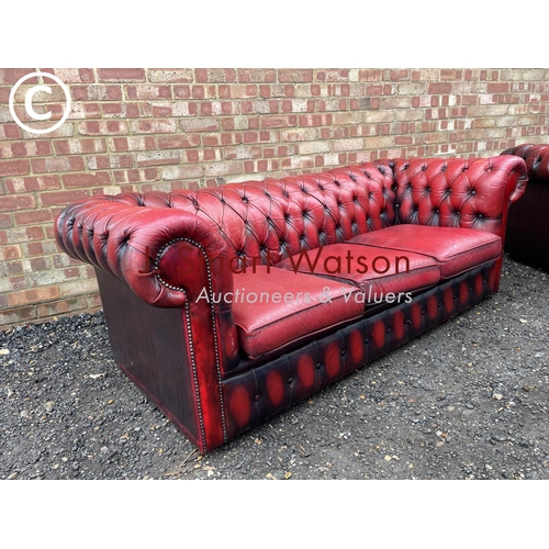 1 - An oxblood red leather chesterfield three seater sofa together with matching club style armchair