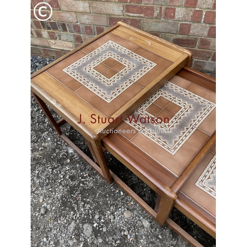 105 - A teak tile top nest of three tables