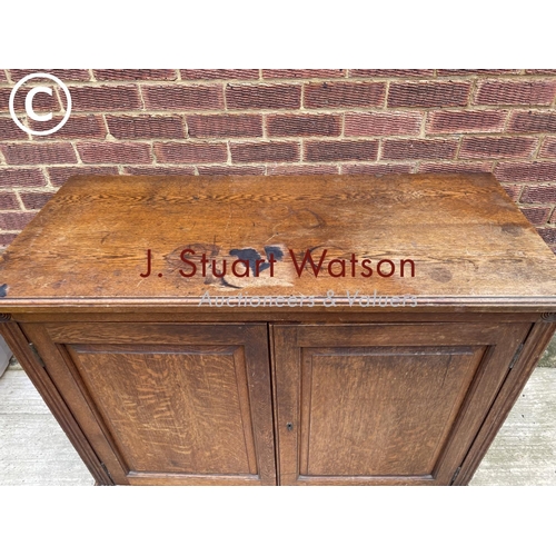 122 - An Edwardian oak two door school cupboard with two internal shelves