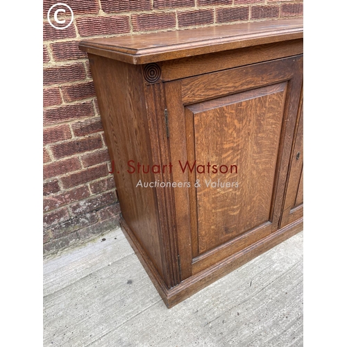 122 - An Edwardian oak two door school cupboard with two internal shelves